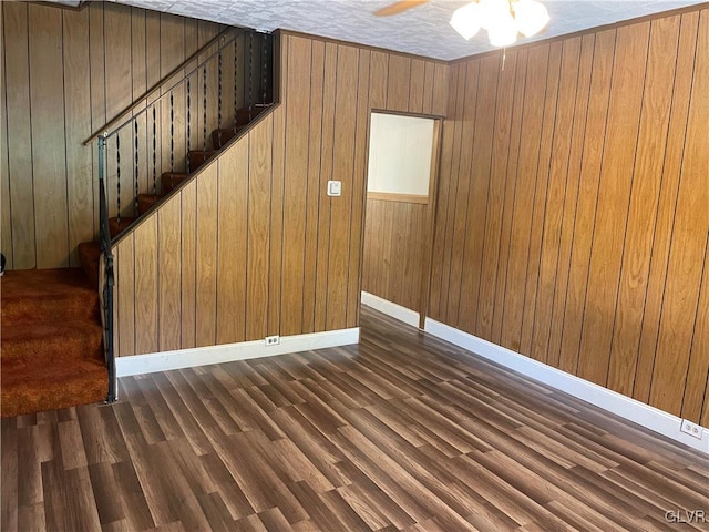 interior space featuring wooden walls, ceiling fan, and dark wood-type flooring