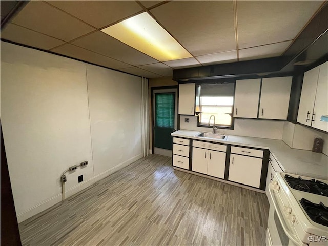 kitchen featuring white cabinets, sink, white gas range, a drop ceiling, and light hardwood / wood-style floors