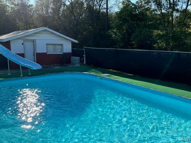 view of swimming pool with an outdoor structure and a water slide