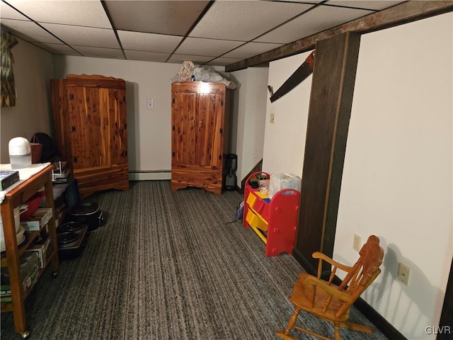 recreation room with a paneled ceiling, a baseboard heating unit, and dark carpet