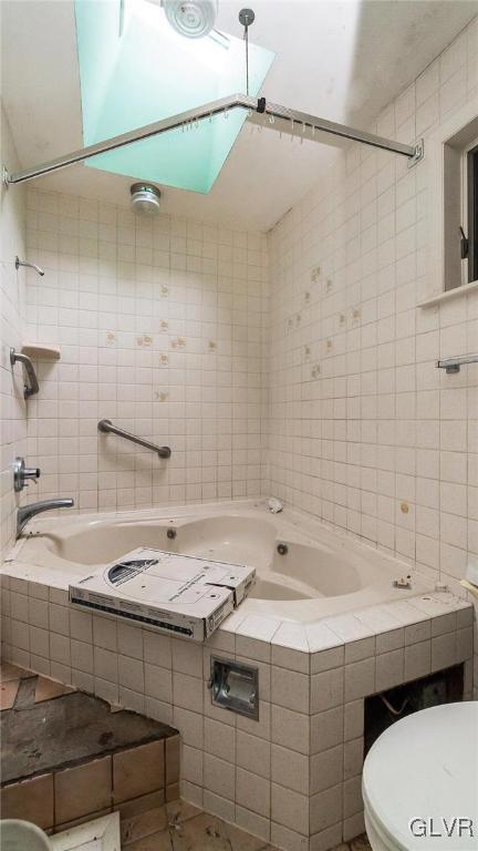 bathroom with tile walls, tiled shower / bath combo, and toilet