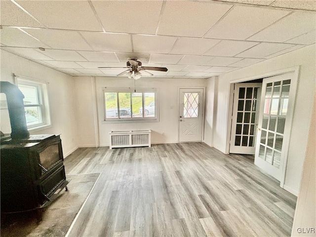 interior space with radiator heating unit, a wood stove, plenty of natural light, and a paneled ceiling