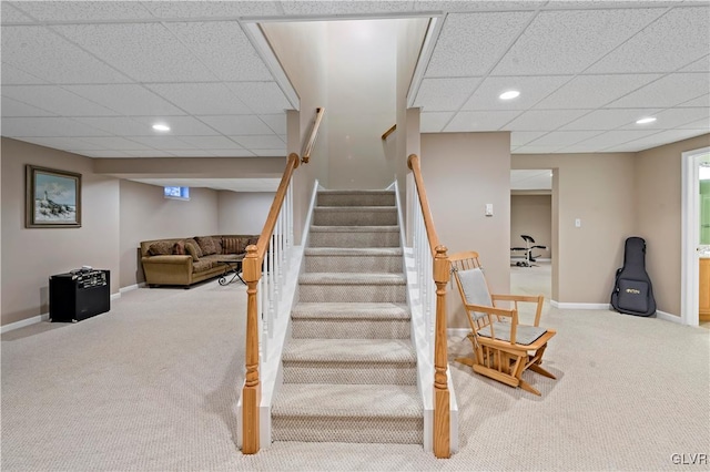 stairway featuring carpet flooring and a drop ceiling