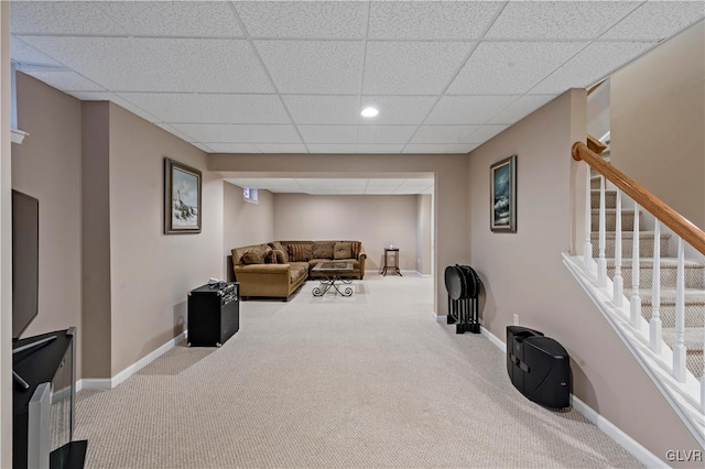 living room featuring a drop ceiling and carpet