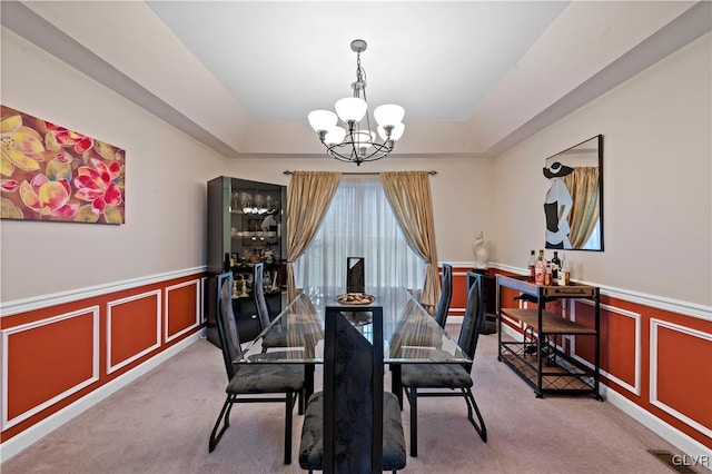 dining room with carpet floors, a raised ceiling, and a chandelier