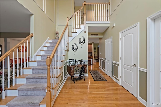 stairway with hardwood / wood-style floors and a high ceiling