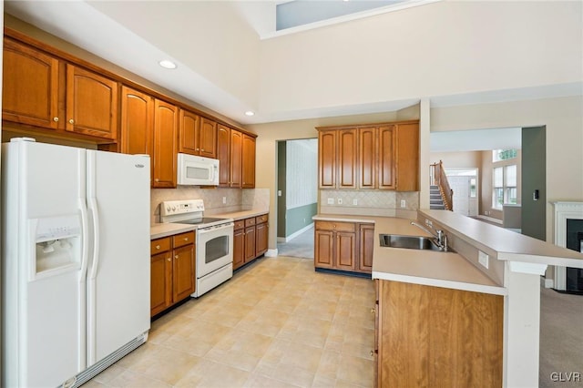 kitchen featuring sink, white appliances, kitchen peninsula, and tasteful backsplash