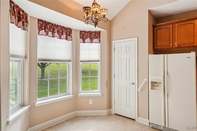 kitchen with decorative light fixtures, lofted ceiling, white fridge with ice dispenser, and a notable chandelier