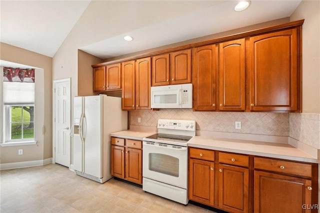 kitchen featuring vaulted ceiling, decorative backsplash, and white appliances