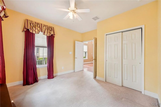 unfurnished bedroom with ceiling fan, light colored carpet, a closet, and multiple windows