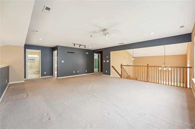 empty room featuring ceiling fan with notable chandelier, track lighting, lofted ceiling, and carpet floors