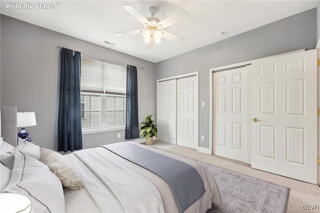 bedroom featuring ceiling fan, carpet, and multiple closets