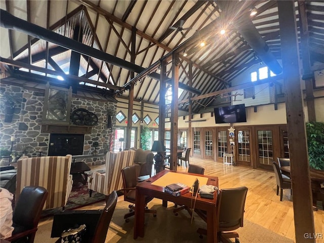 dining space featuring high vaulted ceiling, hardwood / wood-style floors, beamed ceiling, and a fireplace