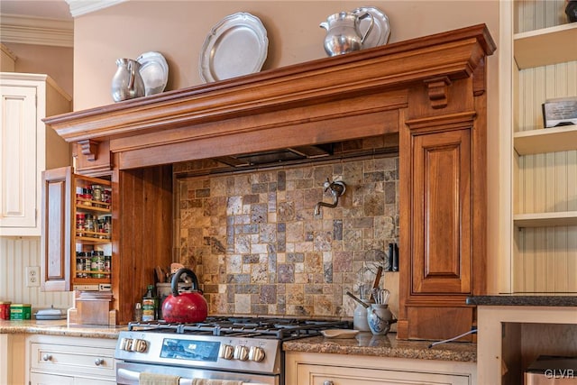 kitchen with dark stone counters, crown molding, tasteful backsplash, and stainless steel range