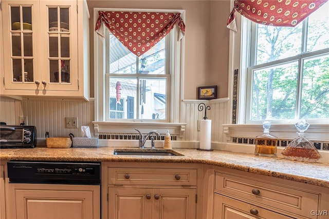 kitchen with light stone countertops, dishwashing machine, and sink