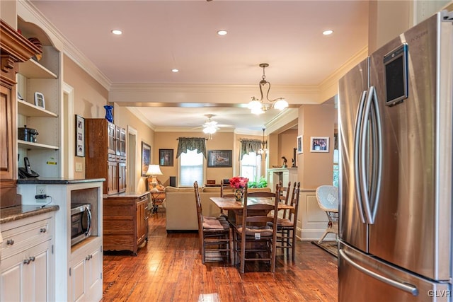 dining space featuring ceiling fan with notable chandelier, ornamental molding, and dark hardwood / wood-style floors