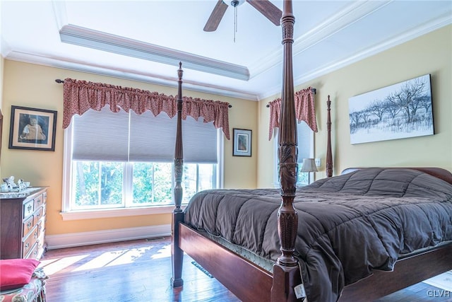 bedroom featuring wood-type flooring, ceiling fan, a raised ceiling, and crown molding