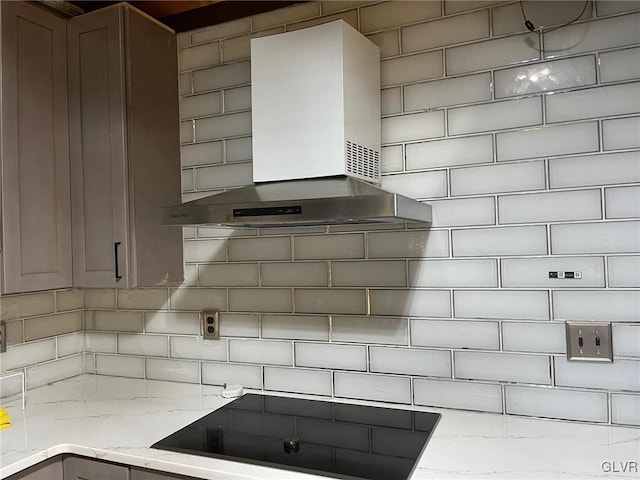 details with tasteful backsplash, light stone counters, wall chimney exhaust hood, and black stovetop