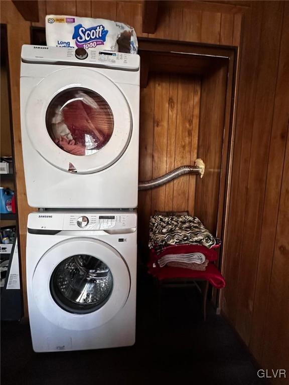 laundry area with stacked washing maching and dryer and wood walls