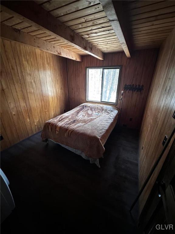 bedroom featuring beam ceiling, wood ceiling, dark wood-type flooring, and wood walls