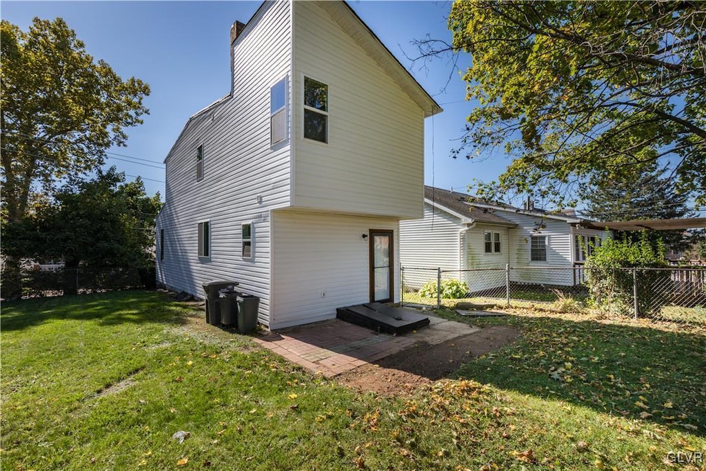 back of house with a lawn and a patio