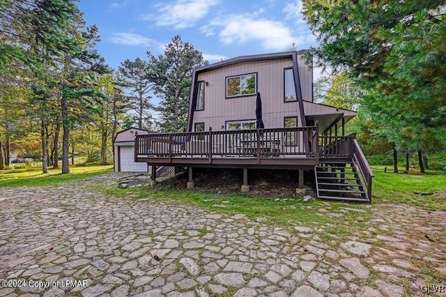 back of house featuring a deck, an outdoor structure, and a garage