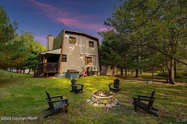 back house at dusk with an outdoor fire pit and a yard