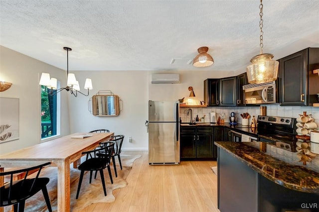 kitchen featuring appliances with stainless steel finishes, hanging light fixtures, light hardwood / wood-style floors, tasteful backsplash, and a chandelier