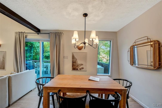 dining area featuring light wood-type flooring, a textured ceiling, and a chandelier