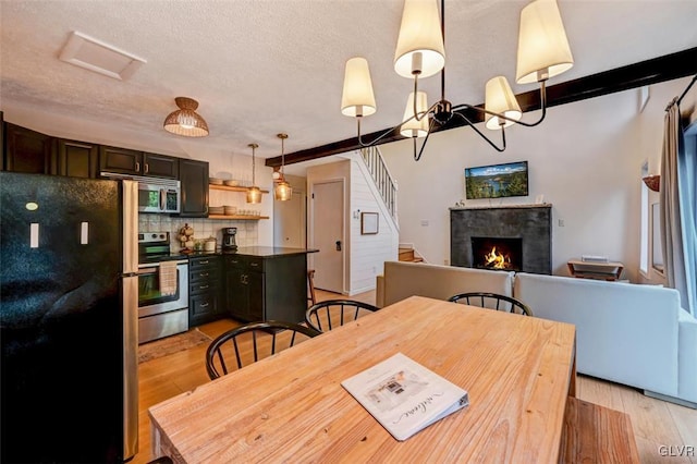 kitchen featuring hanging light fixtures, decorative backsplash, stainless steel appliances, light wood-type flooring, and dark brown cabinets