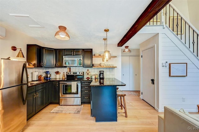 kitchen featuring appliances with stainless steel finishes, hanging light fixtures, light hardwood / wood-style floors, tasteful backsplash, and a breakfast bar area