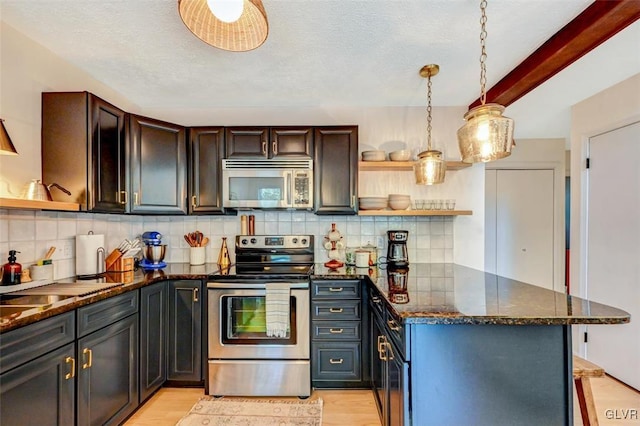 kitchen with appliances with stainless steel finishes, dark brown cabinetry, dark stone countertops, and light wood-type flooring