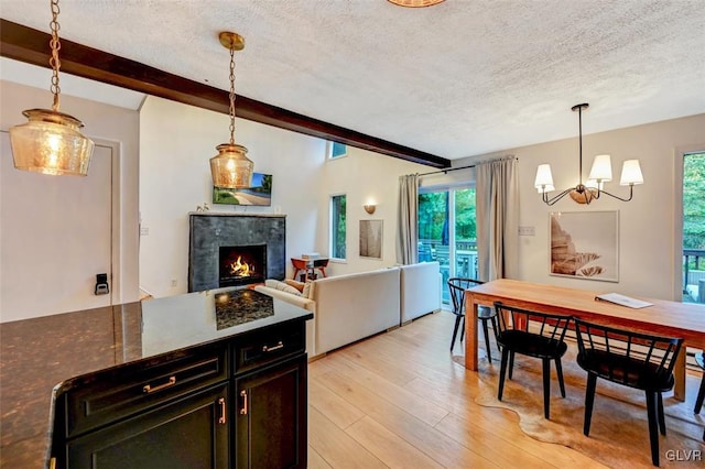 kitchen featuring a tiled fireplace, beamed ceiling, and hanging light fixtures