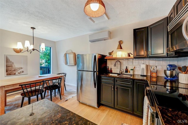 kitchen featuring light hardwood / wood-style floors, tasteful backsplash, an AC wall unit, an inviting chandelier, and stainless steel appliances