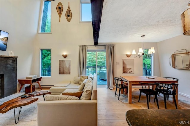 living room featuring light wood-type flooring, a textured ceiling, and an inviting chandelier