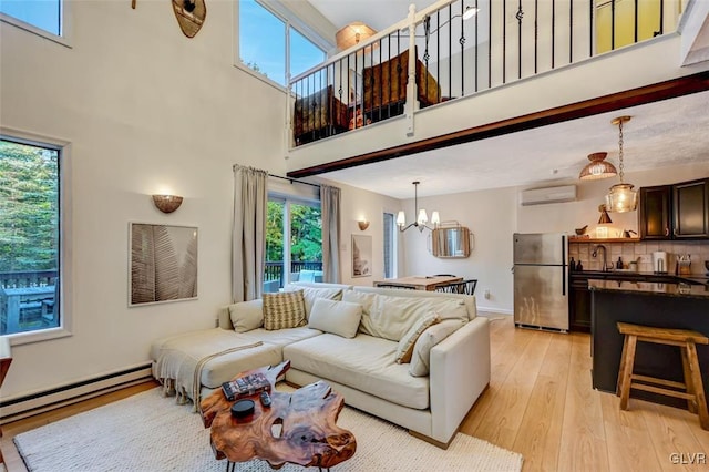 living room with light wood-type flooring, a high ceiling, an AC wall unit, and a wealth of natural light