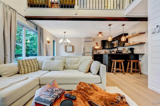 living room featuring an inviting chandelier, light wood-type flooring, and an AC wall unit