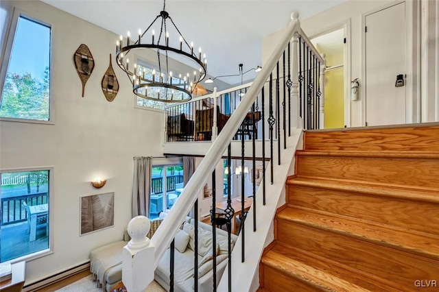 stairs with wood-type flooring, a chandelier, and a baseboard heating unit