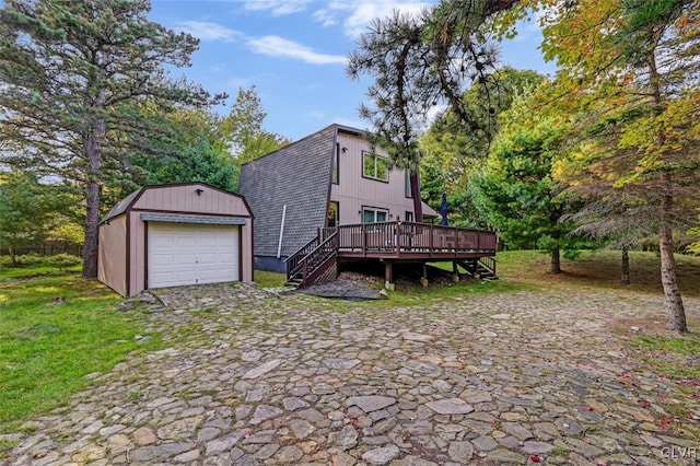 rear view of property featuring a deck, an outdoor structure, and a garage