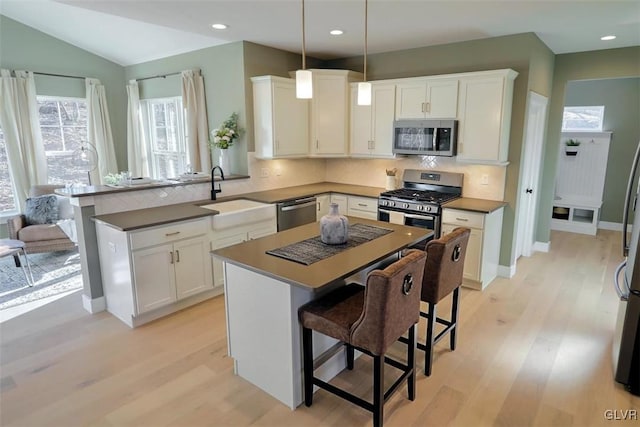 kitchen featuring a center island, stainless steel appliances, decorative light fixtures, and sink