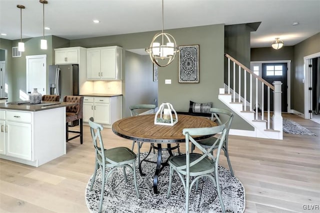 dining room with light hardwood / wood-style floors and an inviting chandelier