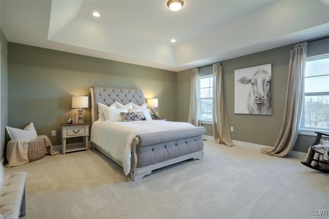 bedroom with a raised ceiling and light colored carpet