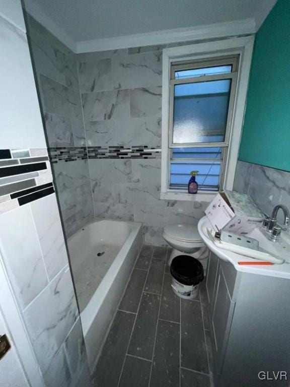 bathroom featuring tile walls, a bathtub, sink, ornamental molding, and toilet