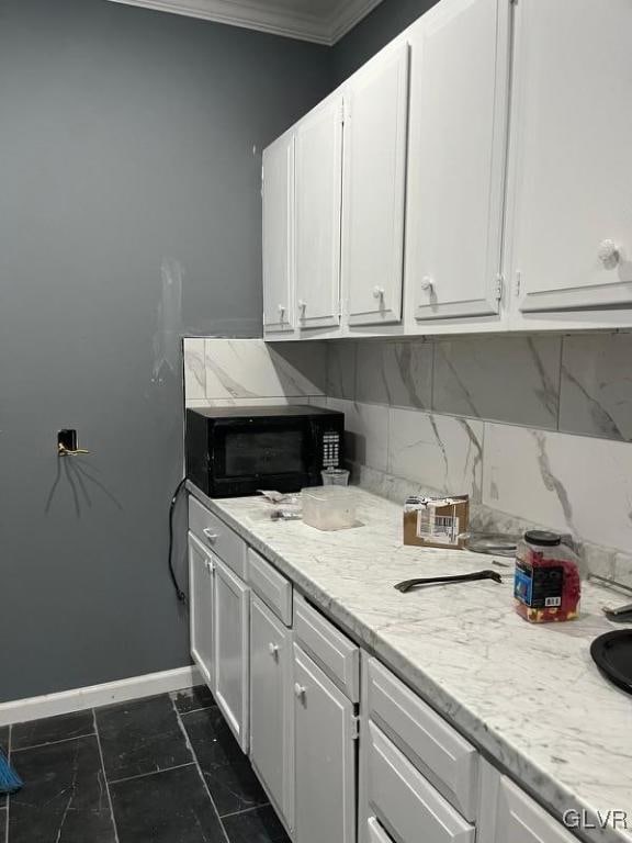 kitchen featuring light stone counters, white cabinets, ornamental molding, and tasteful backsplash