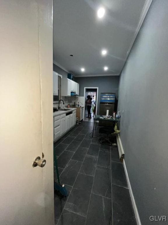 kitchen featuring white cabinetry, crown molding, and sink