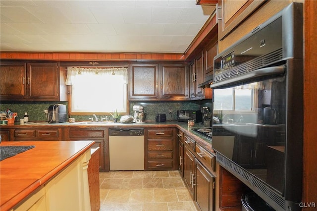 kitchen with decorative backsplash, a healthy amount of sunlight, and dishwashing machine