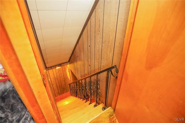 stairs with wooden walls and hardwood / wood-style flooring