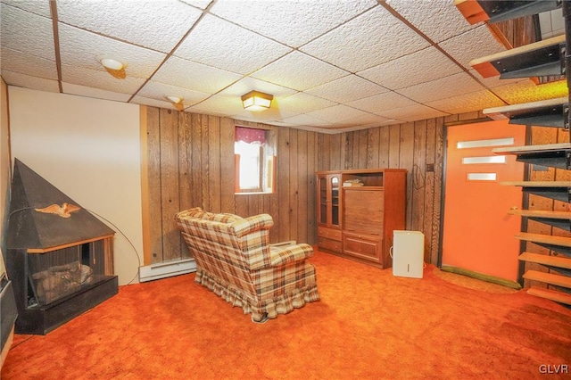 sitting room featuring carpet floors, wooden walls, and a baseboard heating unit