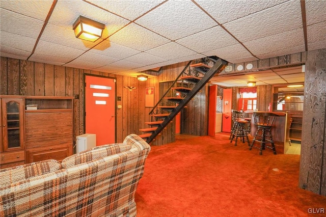 unfurnished living room featuring wood walls, carpet flooring, and bar