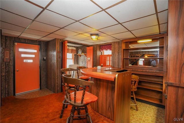 bar featuring a paneled ceiling, carpet, and wooden walls